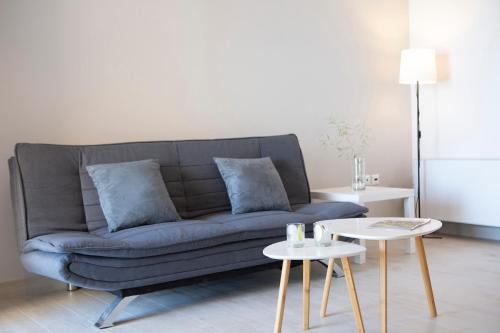 a living room with a blue couch and two tables at Sea n' Smile in Apolpaina