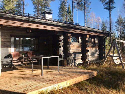 Cabaña de madera con mesa en la cubierta en Mäntyharju-mökki, en Syöte