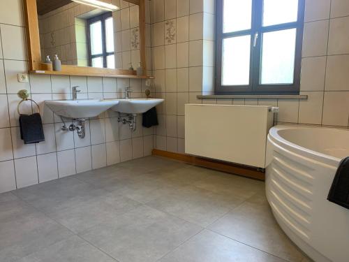 a bathroom with two sinks and a tub and a mirror at Villa mit Pool und Grillplatz in Regensburg in Regensburg
