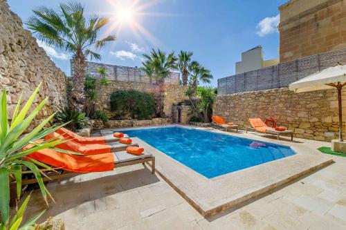 a swimming pool in a yard with chairs and a building at Djar Ta Menzja 1 Holiday Home in Sannat