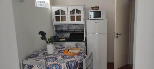 a small kitchen with a table and a white refrigerator at Mar Rosa - Terraço Vista Praia in Horta