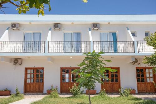 Edificio blanco con puertas de madera y balcón en Karpaz Sunset Hotel, en Rizokarpaso