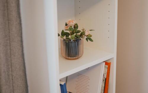 a vase with pink flowers sitting on a shelf at Rozenstein design residence in Brocēni