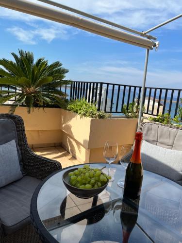 una mesa de cristal con un tazón de uvas y una botella de vino en Candia Hotel en La Canea