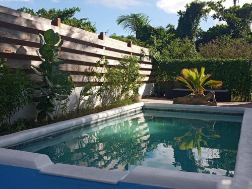 a swimming pool in front of a wooden fence at Beach house with nice private pool ,baie orientale in Orient Bay