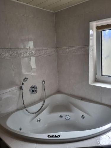 baño con bañera blanca y ventana en Schöne Unterkunft mit Whirpool nahe Phantasialand, en Weilerswist