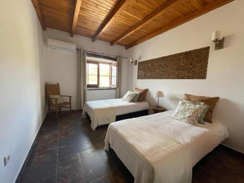 a bedroom with two beds and a wooden ceiling at Corvatos Casas do Monte in Almodôvar