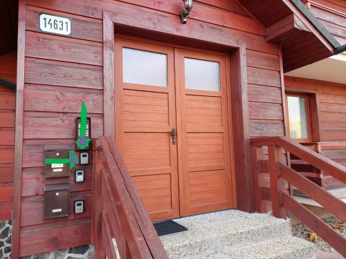 a front door of a wooden cabin with a staircase at Apartman Tatry in Tatranská Lomnica