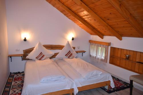 a bedroom with a bed with white sheets and wooden ceilings at Clematis House in Voronet