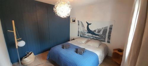 een slaapkamer met een blauw bed en een kroonluchter bij Maison Joli Soir à Ambleteuse in Ambleteuse