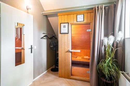 a hallway with a wooden door and a plant at Coco Wellness Bungalow in Ewijk