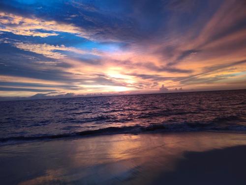 a sunset on the beach with the ocean at Neela Waters - Beach Home in Alleppey