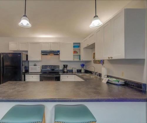 a kitchen with white cabinets and a counter with two blue chairs at Living the Dream 2 Bedroom Ocean View Cozy Condo in Gulf Shores