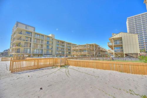 a building on the beach with a fence and buildings at Living the Dream 2 Bedroom Ocean View Cozy Condo in Gulf Shores