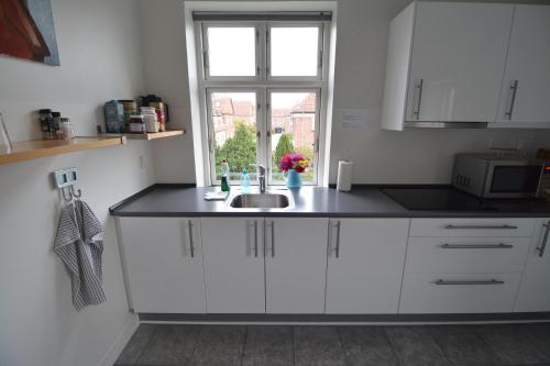 a white kitchen with a sink and a window at Billesgade Rooms in Odense