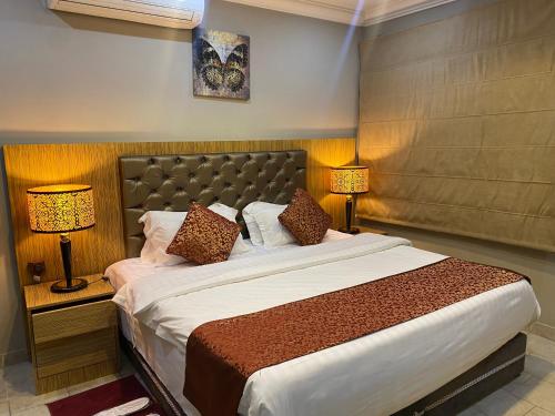 a bedroom with a large bed with two lamps at Garden City 2 in Riyadh