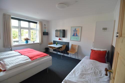 a bedroom with two beds and a table and a window at Billesgade Rooms in Odense