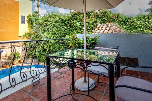 a glass table and chairs on a balcony with an umbrella at Casa del Sol Inn in Ajijic
