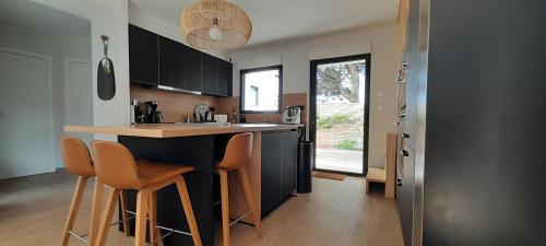 a kitchen with a counter and some chairs in it at Maison Joli Soir à Ambleteuse in Ambleteuse