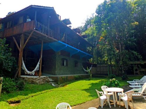 una casa con un patio con sillas y un porche en Pousada Santa Clara, en Visconde De Maua