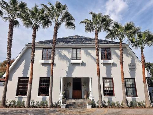 una casa blanca con palmeras delante en 5 Seasons Guest House, en Stellenbosch