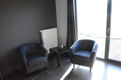 two chairs and a table in a room with a window at La Chambre Du Pèlerin in Foy-Notre-Dame