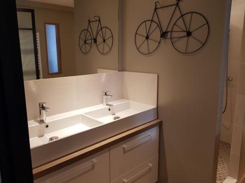 a bathroom with a sink and two bikes on the wall at ilederesibois in Les Portes