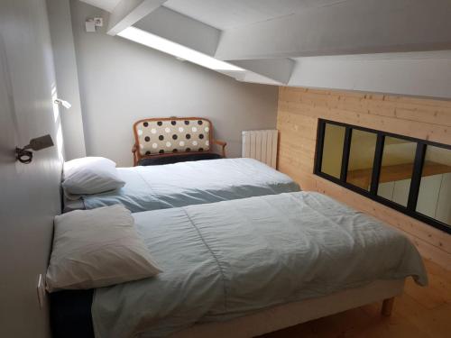 a bedroom with two beds and a chair at ilederesibois in Les Portes