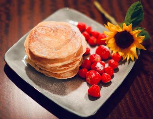 a plate with pancakes and strawberries and a sunflower at Ailim House Serviced Cottage Escape, around the corner from the Old Course in St. Andrews
