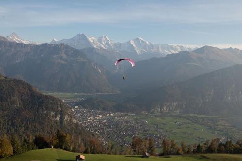 a person flying a kite over a valley with mountains at Wengen Lauberhorn - Flat available in Wengen