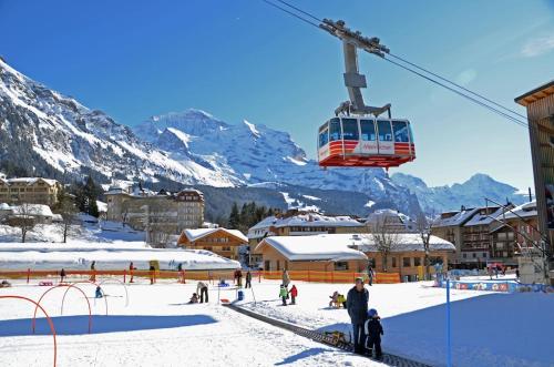 a ski resort with a ski lift in the mountains at Wengen Lauberhorn - Flat available in Wengen