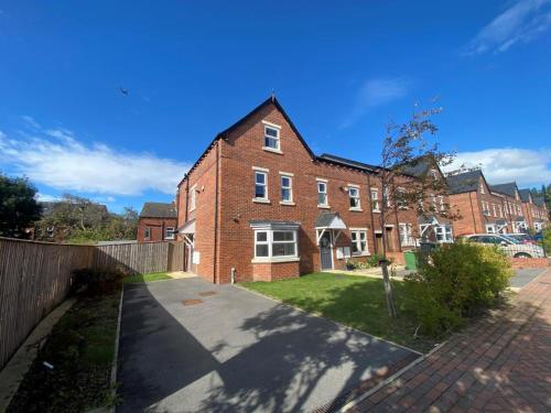 a large brick house with a driveway in front of it at Deluxe City Centre 4 Bedroom Entire Town House in Leeds