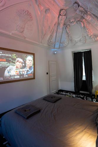 a bedroom with a large bed with a tv on the ceiling at Capsule Art Déco - Jacuzzi - Netflix - Home Cinéma - Arcade de jeux & Nintendo switch - 2 chambres - Filet suspendu in Valenciennes