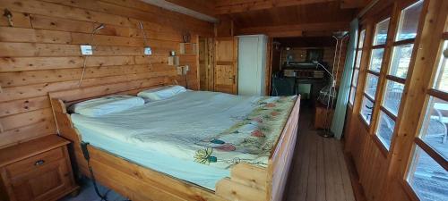 een slaapkamer met een bed in een houten hut bij Ruime romantische blokhut in Zwaanshoek