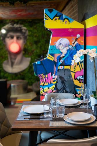 a table with plates and glasses on top at Capsule Art Déco - Jacuzzi - Netflix - Home Cinéma - Arcade de jeux & Nintendo switch - 2 chambres - Filet suspendu in Valenciennes