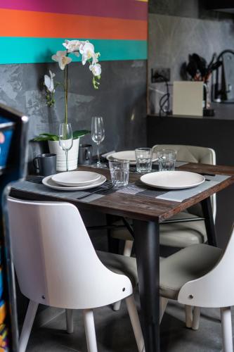 a wooden table with white plates and chairs at Capsule Art Déco - Jacuzzi - Netflix - Home Cinéma - Arcade de jeux & Nintendo switch - 2 chambres - Filet suspendu in Valenciennes