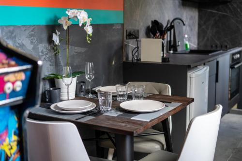 a table with plates and glasses on it in a kitchen at Capsule Art Déco - Jacuzzi - Netflix - Home Cinéma - Arcade de jeux & Nintendo switch - 2 chambres - Filet suspendu in Valenciennes
