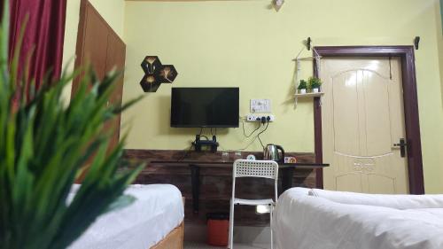 a living room with a television and a desk with a chair at Urbanica Homestay in Guwahati