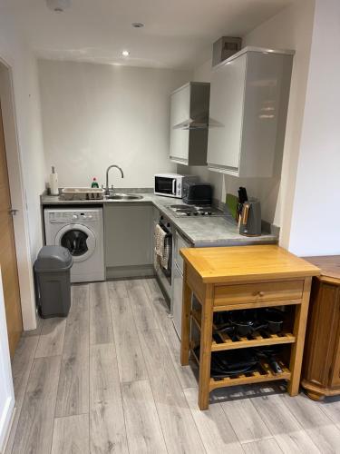 a kitchen with a stove and a sink and a table at Lovely, Sleeps 8, Parking, Cafe Bars Shops Beach Train, Central Formby in Formby