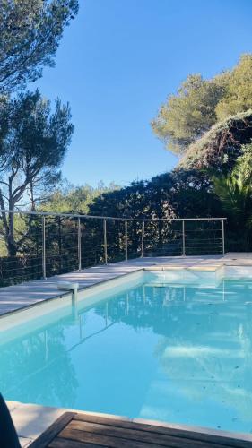 une piscine d'eau bleue en face d'une clôture dans l'établissement Villa piscine 6km de Cassis 12 couchages, à Roquefort-la-Bédoule