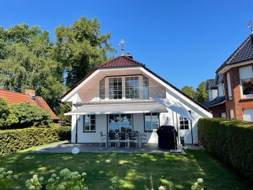 a white house with chairs and tables in a yard at Meerblick Pelzerhaken in Neustadt in Holstein