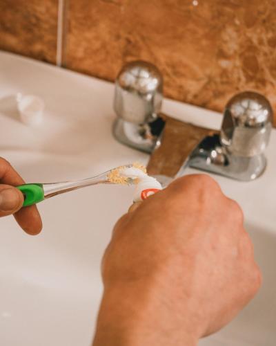 a person holding a toothbrush in front of a sink at Wild Incas Hostel in Cuenca