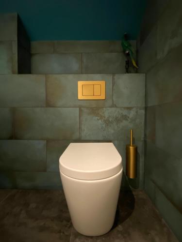 a white toilet in a bathroom with a tile wall at Ailim House Serviced Cottage Escape, around the corner from the Old Course in St. Andrews