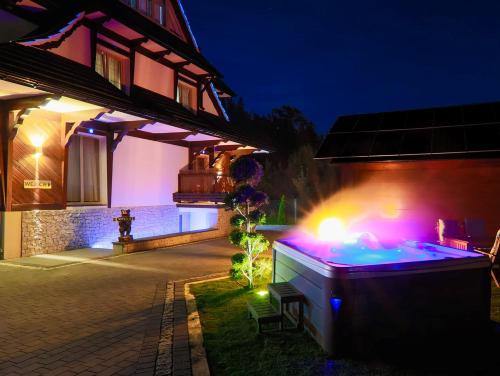 ポロニンにあるGÓRALSKA VILLA APARTAMENTY Z JACUZZI & HOME SPA & Zakopaneの夜の家の庭にあるホットタブ