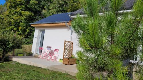 a small white shed with red chairs in the yard at Studio Cosy in Nazelles