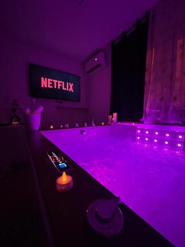 ein lila Zimmer mit einer Badewanne und einem Netflix-Schild in der Unterkunft Love Room à Cannes - Appartement 25m2 pour 2 personnes avec un jacuzzi Privé in Cannes