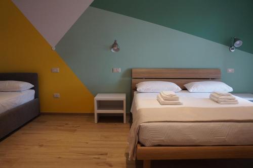 2 camas en una habitación con una pared verde y amarilla en La Sperella Bed and Breakfast, en Fermo
