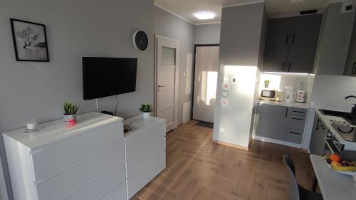 cocina con armarios blancos y TV en la pared en Apartament Orla 47F Perłowa Dolina en Bydgoszcz