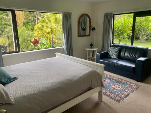 a bedroom with a bed and a couch and windows at Harbour View Retreat Mangonui in Mangonui