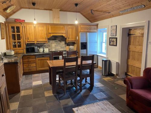 a kitchen with wooden cabinets and a table and chairs at John the mills cottage spaHot tub private beach in Donegal